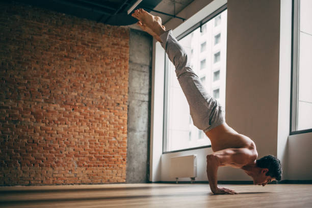 istock Young man doing yoga handstand in big bright training gym 1134862672