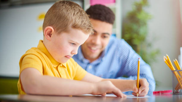 istock primary schoolchild with graduate teacher 1134864215