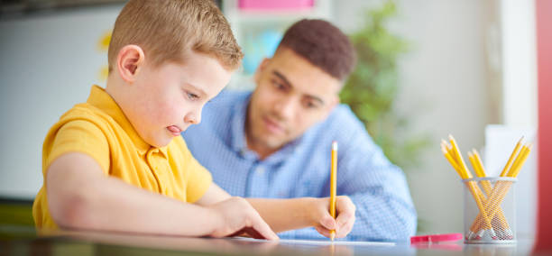 istock primary schoolchild with graduate teacher 1134865106