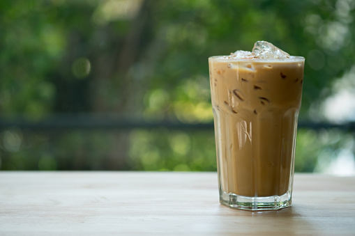 Iced espresso coffee in tall shape glass on wooden table, refreshing drink