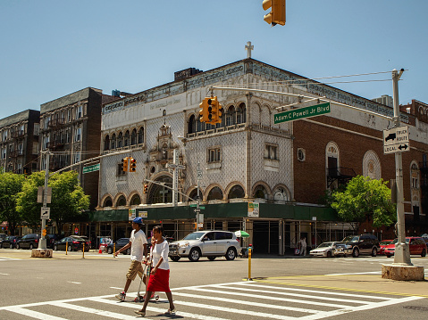 New York - United States June 17, 2014 - People walking on a crosswalk on a street of Harlem neigborhood in New York