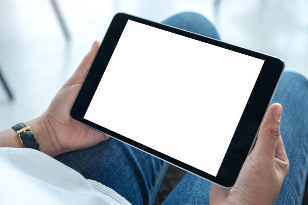 istock Mockup image of a woman holding black tablet pc with blank white screen horizontally while sitting in cafe 1134867636