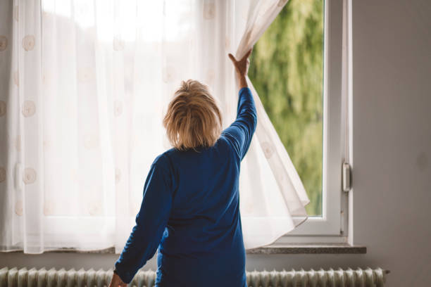 istock Woman opening curtains and looking out 1134867669