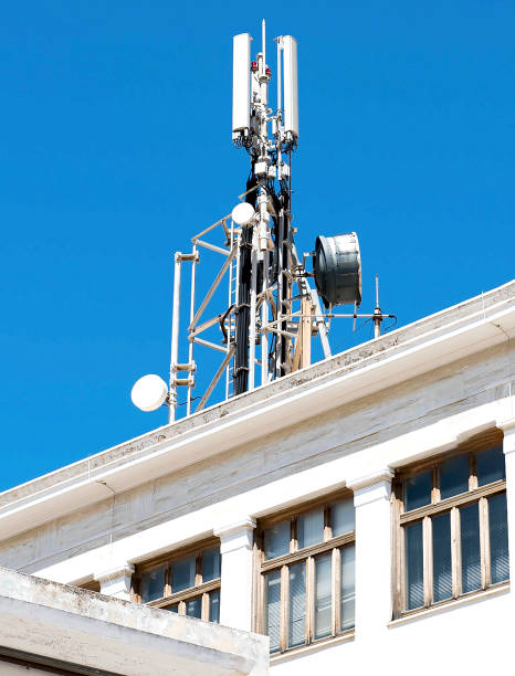 Cell phone telecommunications antennas and repeaters on building against clear blue sky