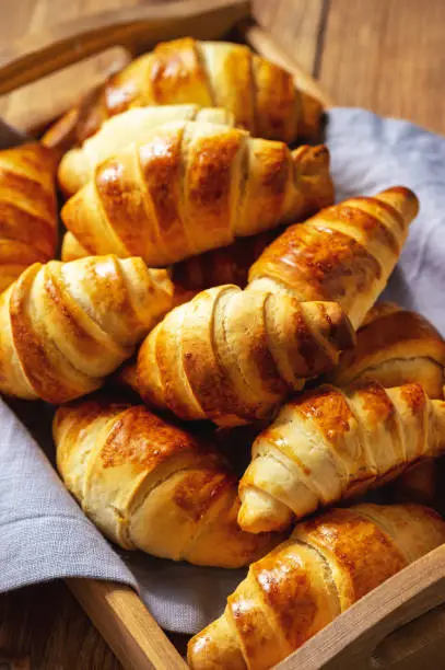 Photo of Homemade butter croissants on wooden tray.