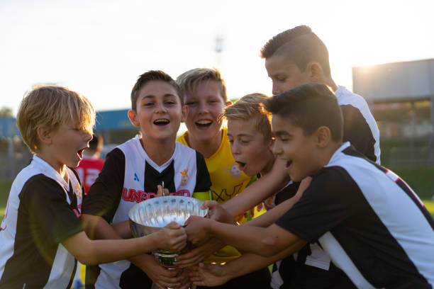 happy successful junior soccer players with trophy - youth league imagens e fotografias de stock