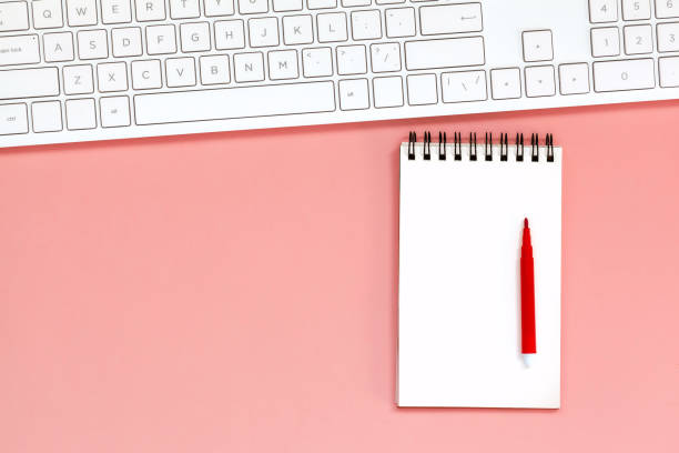 istock Workspace with Blank spiral notebook with keyboard on Coral Background. Top view 1134877811