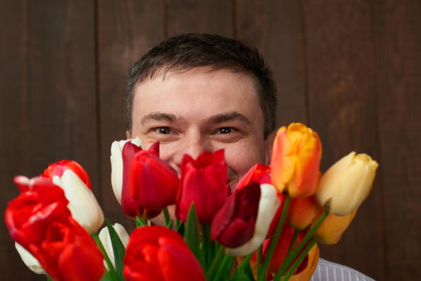 Man face is behind tulip flowers