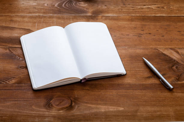 istock Open blank empty paper notebook with pen on brown wooden desk,  note book pad pages for memo writing writer workplace creative business work table background, top view, copy space 1134882334