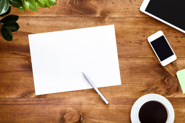istock Work space desk with empty white blank paper sheet for notes pen and devices on brown wooden table writer workplace creative business goals to do list background, top view, copy space 1134882336
