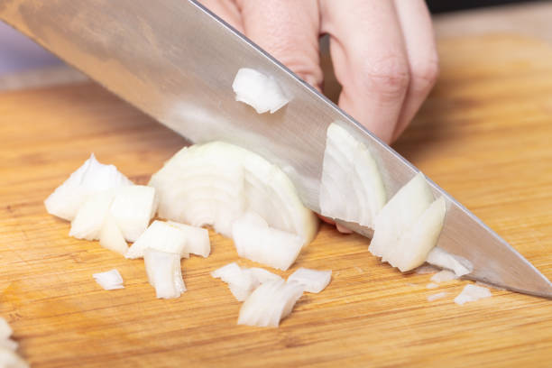 istock cook cuts onion on a wooden board 1134884284