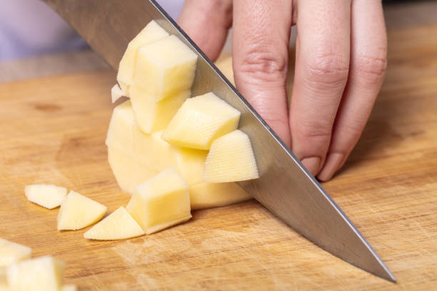 istock cook cuts potatoes on a wooden board 1134885170