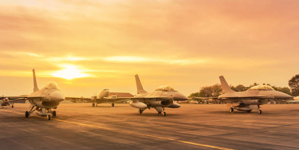 Row of military fighter jet aircraft parked on runway on sunset Row of military fighter jet aircraft parked on runway in the base airforce standby ready to take off for military mission on sunset military base stock pictures, royalty-free photos & images