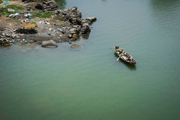 fisher boat on still lake with trash on lakeside