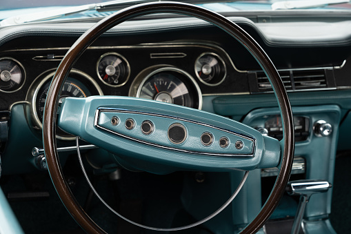 Steering wheel of a classic american car. Showing part of the interior and the dash board