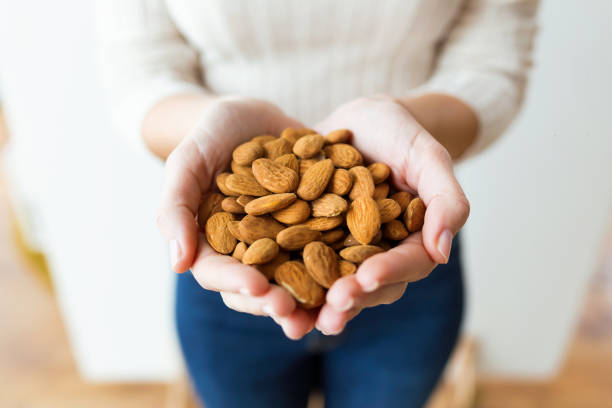 istock Young woman hands holding and showing almonds nuts at home. 1134890136