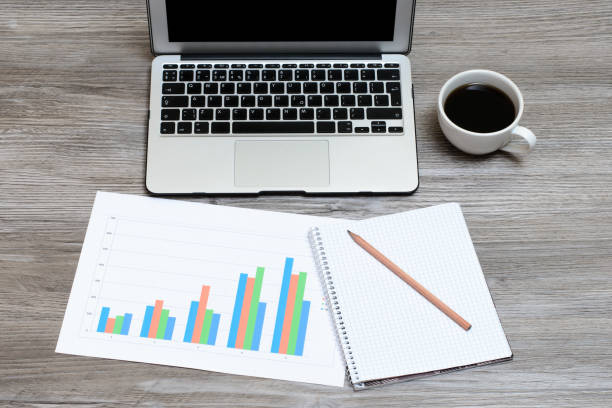 istock Overhead view on the wooden table laptop, notebook, pencil, graphics on it 1134890396