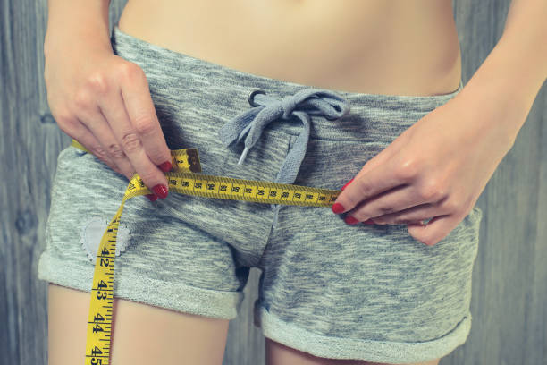 istock Woman measuring her hips using yellow tape measure 1134891101