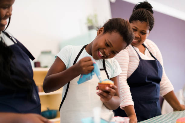 istock Young girl icing cupcakes with mom and aunt in colourful kitchen 1134891328