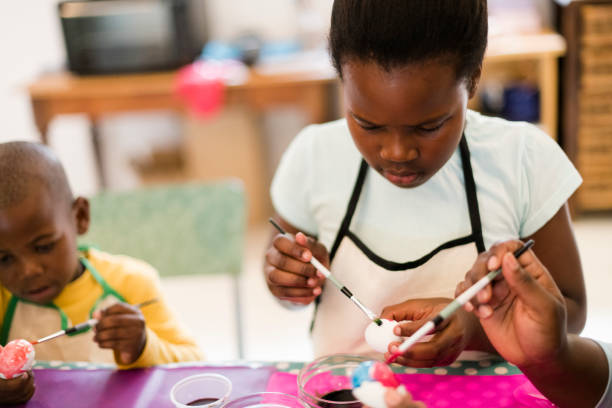 istock Young African girl concentrates as she paints Easter eggs with brother 1134891417