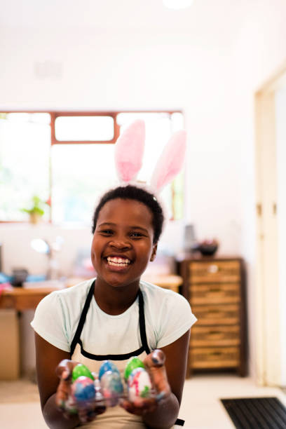 istock Smiling girl wearing Easter bunny ears holding up hand painted Easter eggs 1134891672