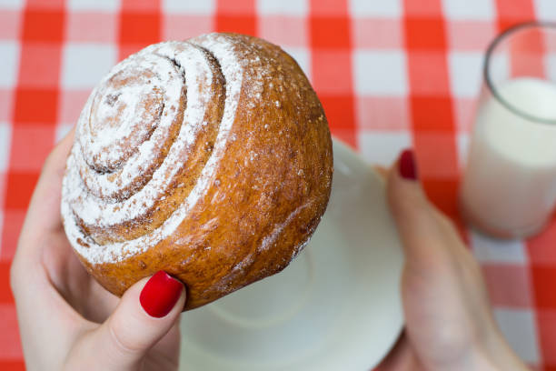 istock Person is going to bite tasty sweetie cinnamon roll 1134891850
