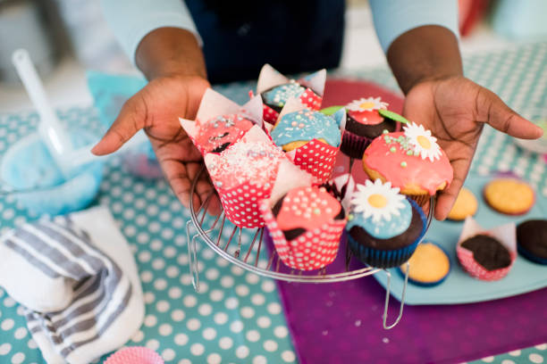 Close up hands hold out brightly decorated homemade cupcakes
