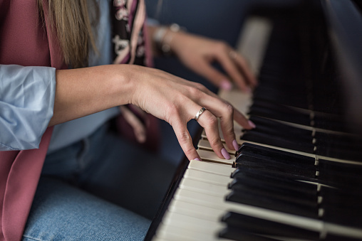 Young woman playing piano hand close up.
