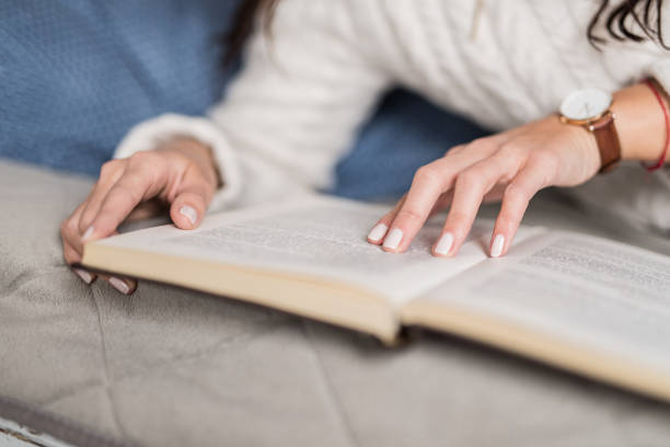 istock Unrecognizable young woman reading a book at home. 1134893428