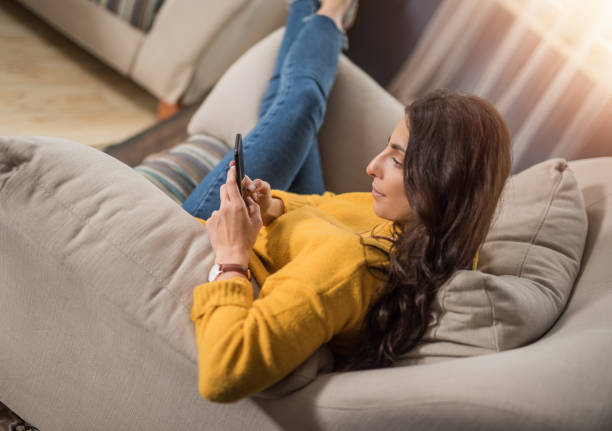 istock Beautiful curly young woman using a phone at home. 1134895992
