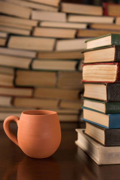 istock cup and many books on a wooden table 1134900078