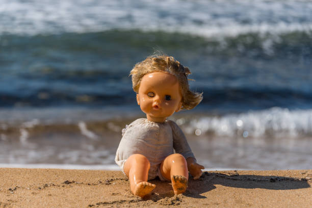 istock Old Broken Toy Doll Sitting on a Beach in Italy 1134901334