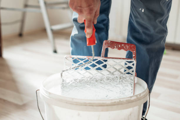 Man removes excess paint from the paint roller Man removes excess paint from the paint roller house painter ladder paint men stock pictures, royalty-free photos & images