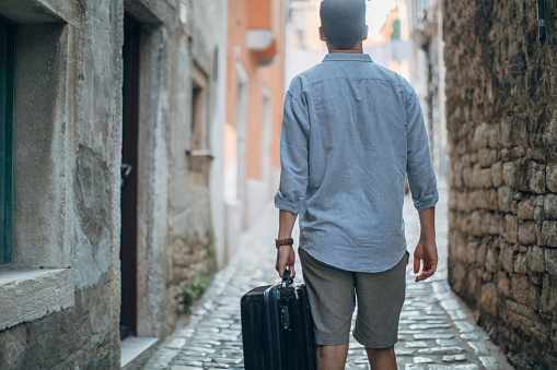 Tourist man walking with suitcase in Rovinj, Croatia