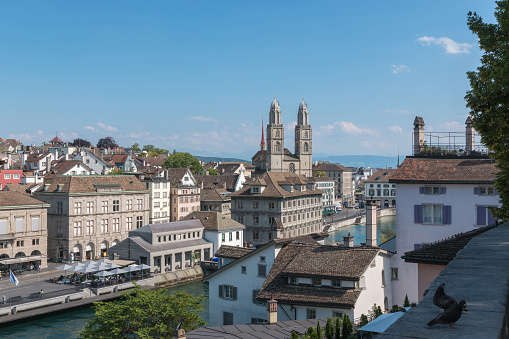 Aerial view of historic Zurich city center with famous Grossmunster Church and river Limmat from Lindenhof park, Zurich, Switzerland. Summer landscape, sunshine weather, blue sky and sunny day