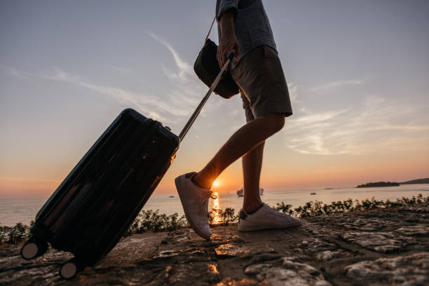 istock Tourist man walking by the sea with suitcase 1134907377