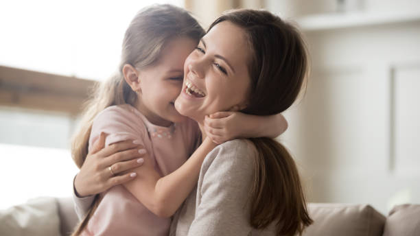 Loving young mother laughing embracing smiling cute funny kid girl Loving young mother laughing embracing smiling cute funny kid daughter enjoying time together at home, happy family single mom with little child girl having fun playing feel joy cuddling and hugging happy day stock pictures, royalty-free photos & images