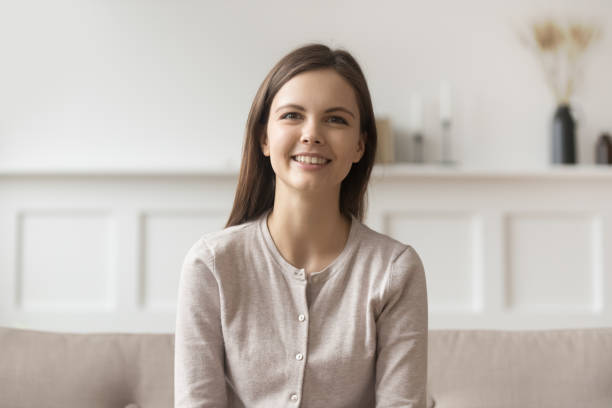 istock Smiling young casual woman sitting on couch looking at camera 1134909514