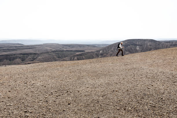 istock Backpacker tourist walking desert mountain ridge landscape. 1134909929