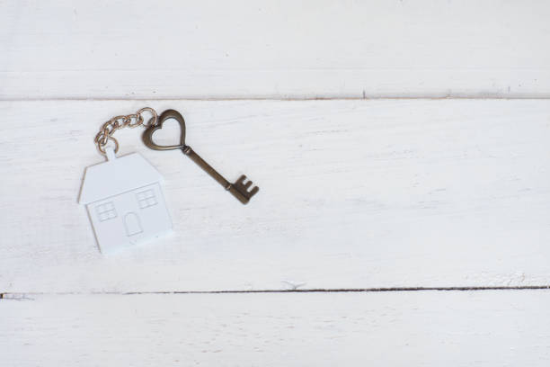 House key in heart shape with home keyring on white wood background, copy space House key in heart shape with home keyring on white wood background, copy space book heart shape valentines day copy space stock pictures, royalty-free photos & images