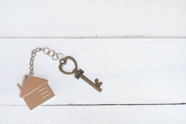 House key in heart shape with home keyring on white wood background, copy space House key in heart shape with home keyring on white wood background, copy space book heart shape valentines day copy space stock pictures, royalty-free photos & images