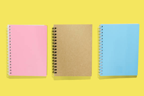 istock Three note books, blue pink and brown paper cover on yellow screen 1134911594