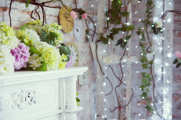 декоративный стол с искусственными цветами и фоном горящих гирлянд - fashionable party design home decorating стоковые фото и изображения