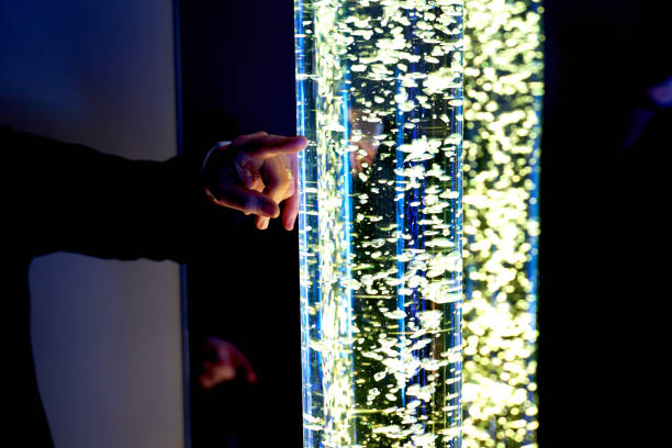 istock therapy sensory stimulating multi sensory room, woman interacting with colored lights bubble tube lamp during therapy session 1134916590