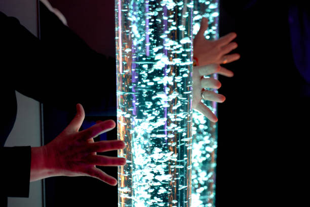 istock therapy sensory stimulating multi sensory room, woman interacting with colored lights bubble tube lamp during therapy session 1134916597