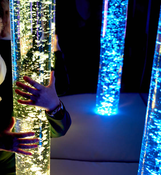 istock therapy sensory stimulating multi sensory room, woman interacting with colored lights bubble tube lamp during therapy session 1134916609