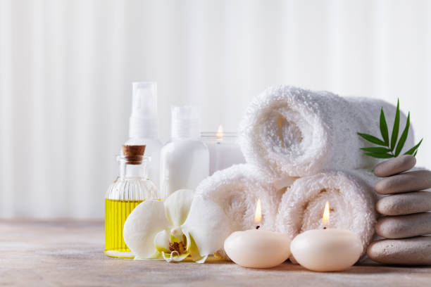 Spa, beauty treatment and wellness background with massage pebbles, orchid flowers, towels, cosmetic products and burning candles. Spa, beauty treatment and wellness background with massage pebbles, orchid flowers, towels, cosmetic products and burning candles. Copy space for text. health spa stock pictures, royalty-free photos & images