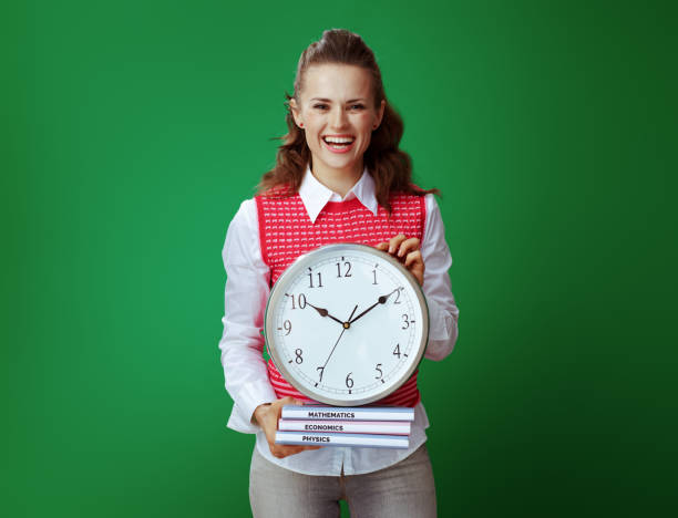istock smiling learner woman showing textbooks and white round clock 1134918102