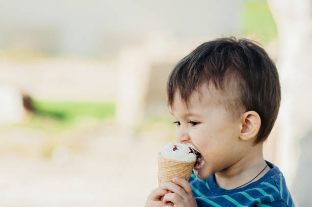 istock baby eating ice cream outdoors on grass background 1134919541