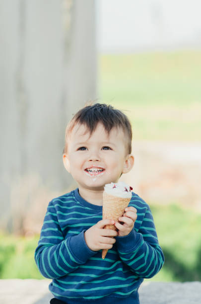 istock baby eating ice cream outdoors on grass background 1134919555